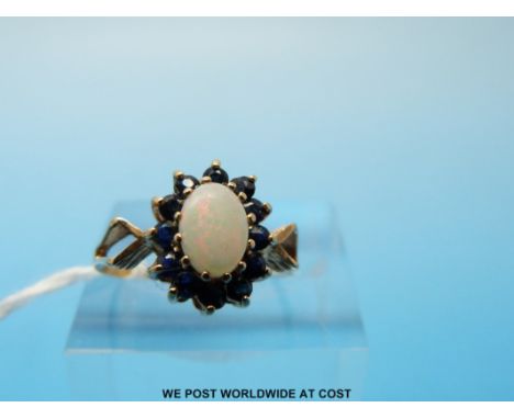 A 9ct gold ring set with an opal cabochon surrounded by sapphires (size L) 