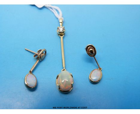 A yellow metal pendant marked 750 set with a round brilliant cut diamond with a drop section holding an oval opal cabochon to