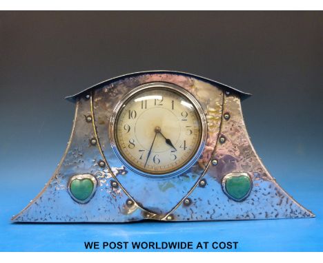 An early 20thC Arts & Crafts plated mantel clock with hammered, riveted design and heart shaped cabochon decoration