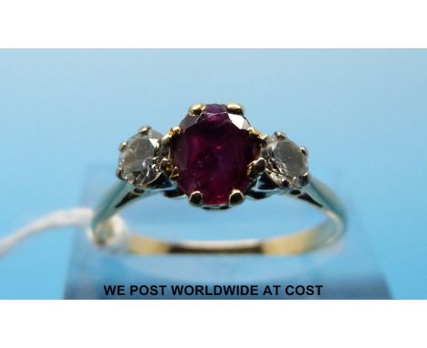 A yellow metal ring set with an oval cut ruby flanked by diamonds (size P) 