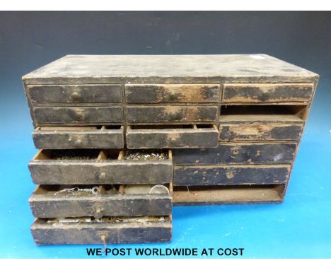 A small vintage set of drawers containing a quantity of wrist and pocket watch spares comprising dials, hands, crowns, spring