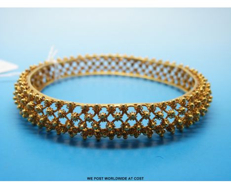 A yellow metal bangle of lattice design with small raised gold spheres (unmarked but possibly 22ct, 45.9g) 