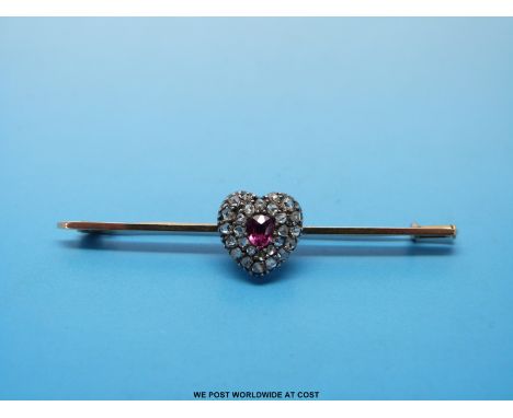 A gold brooch set with rose cut diamonds and a central old cut ruby in a heart shape 