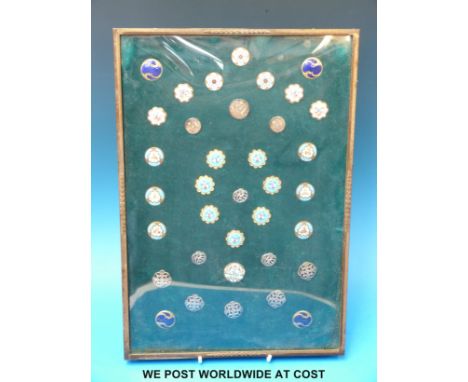 A collection of enamel and silver buttons in a frame, to include hallmarked silver examples