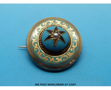 A gold brooch with blue enamel and a seed pearl to the centre and compartment to the back