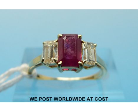 An 18ct gold ring set with an emerald cut ruby of approximately 0.88ct flanked by an emerald cut diamonds each approximately 