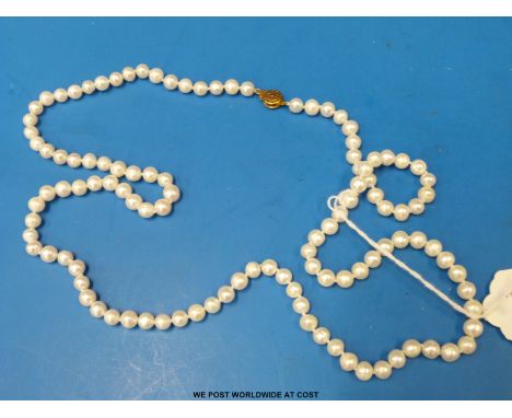 A single strand cultured pearl necklace with a yellow metal clasp 