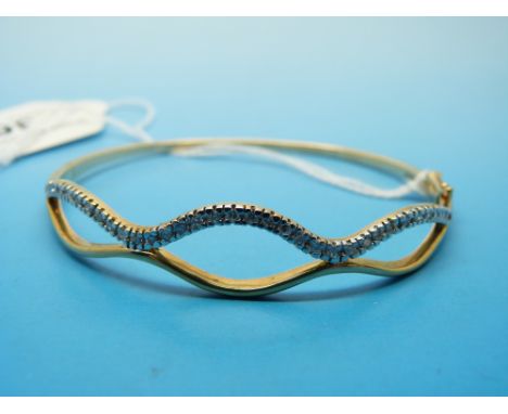 A 9ct gold bangle set with diamonds in a wave design 