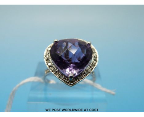 A white metal ring marked 10k set with an amethyst surrounded by diamonds (size N)