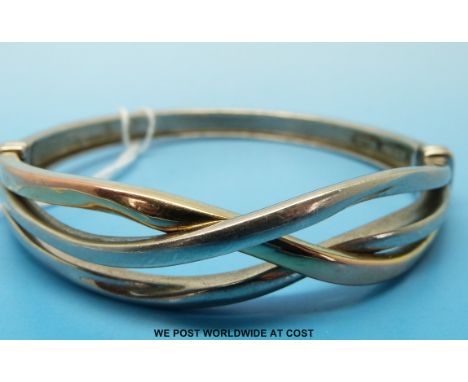 A silver and 9ct gold bangle with intertwined design 