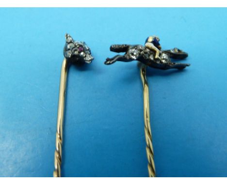 Two yellow metal stick pins, one diamond and enamel formed as a jockey on a horse, the other a diamond mounted fox's head