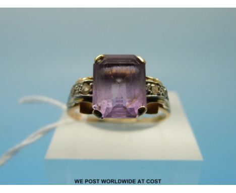 A yellow metal ring set with an emerald cut amethyst and diamonds (size S) 