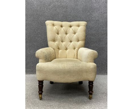 A 19th century button back library armchair having a tapered back with scrolling arms over a serpentine fronted stuffover sea