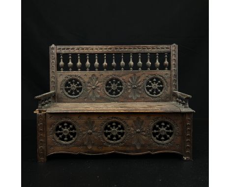 A miniature hand carved 19th century French Breton bench box having a carved and turned spindle back over a moulded seat abov