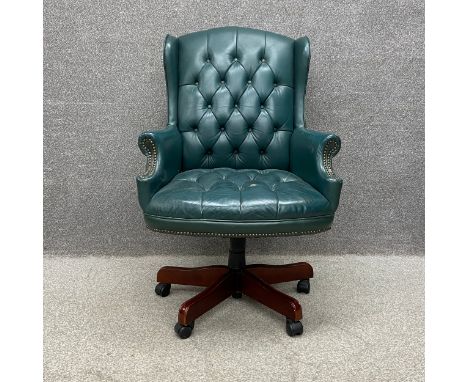A 19th century style green leather button back and stud-work captain's swivel armchair on five mahogany supports on castors. 