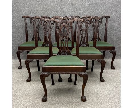 A set of six mahogany Chippendale style dining chairs each having a profusely carved scrolling back and splat over a green up