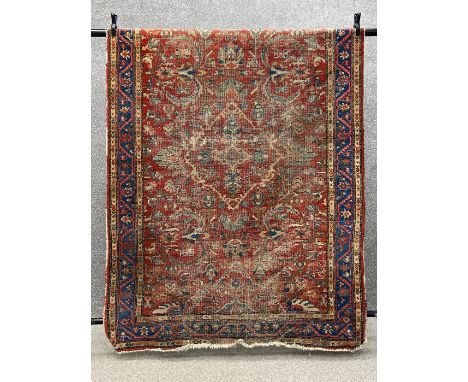 A Persian Heriz carpet having a central lozenge medallion among scrolling foliate designs over an abrash rust ground within b