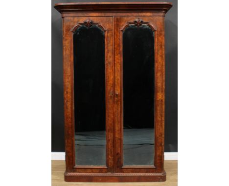 A Victorian walnut wardrobe, outswept cornice above a pair of mirrored doors enclosing a shelf, hanging hooks, sliding trays 