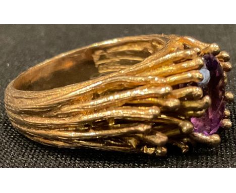 A 9ct gold modernist ring, set with a single oval cut amethyst, surrounded by fronds of gold, size P/Q, 9.1g 