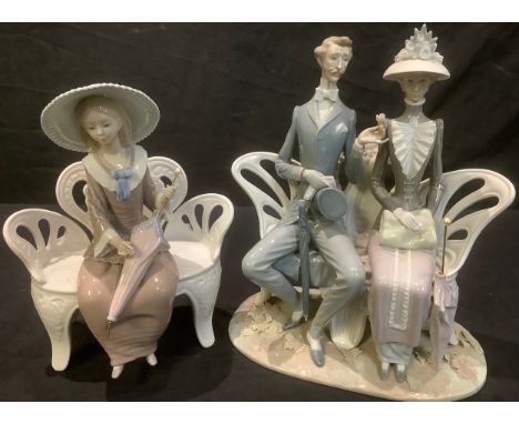 A Lladro figure group, courting couple in Edwardian style dress, seated on a park bench, fallen leaves at their feet, 30.5cm 