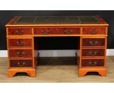 A George III style yew twin pedestal desk, inset tooled and gilt writing surface above three cockbeaded frieze drawers, three