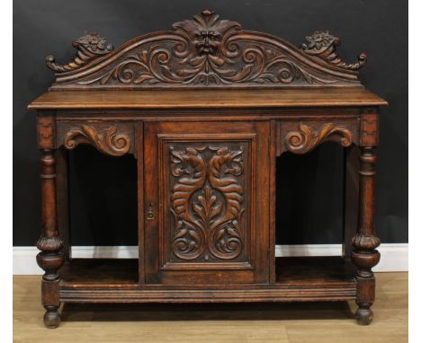 An oak side cabinet, rectangular top with shaped half gallery centred by a Green Man mask flanked by scrolling acanthus and c