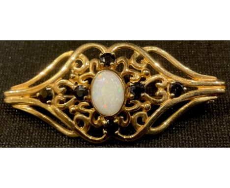 A 9ct gold brooch, set with a central polished opal, surrounded by six smaller sapphires, 4cm, 3.6g 