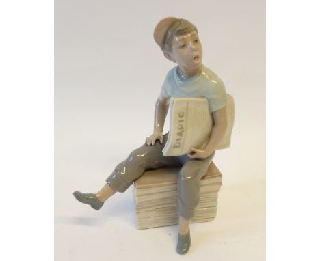 NAO PORCELAIN FIGURE OF A BOY NEWSPAPER VENDOR, seated on a pile of Diario newspapers, 9" (22.9cm) high 