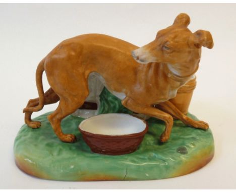 A LATE 19TH CENTURY TINTED BISQUE GROUP, APPREHENSIVE GREYHOUND ALONGSIDE BASKETS AND A BUCKET on an oval base, 7½" (19cm) wi