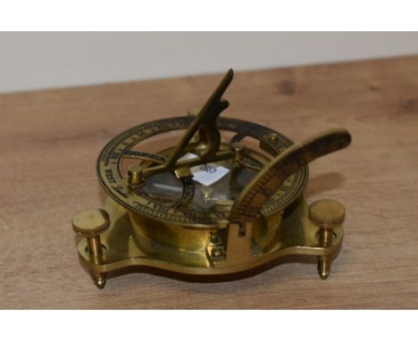 A reproduction brass sundial compass with three adjustable feet