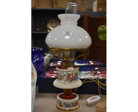A mid-century opaque glass and ceramic oil lamp, decorated having hand coloured flowers and gilt edging, h45cm.