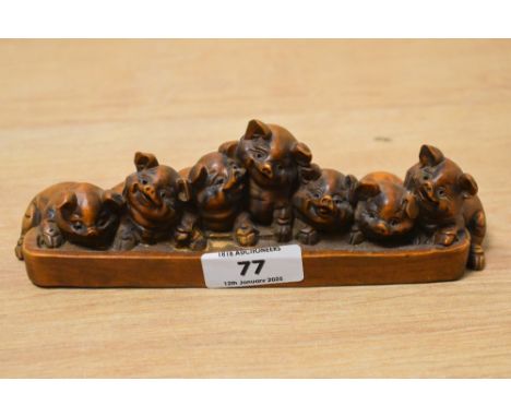 A 20th century Chinese carved boxwood group, depicting seven smiling piglets huddled around a trough, L17cm
