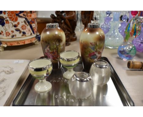 A pair of late 19th / early 20th century miniature porcelain vases, having silver rim and a transferprinted scene depicting a