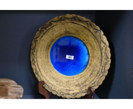 A large earthern ware plate, the centre having a sea blue glaze boarded by a Aztec style pattern, w37cm
