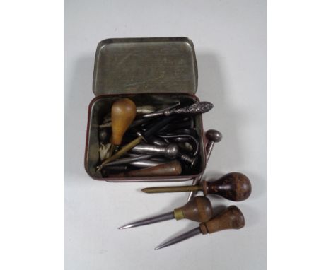 A vintage tin containing silver handled button hook, leatherwork tools etc 