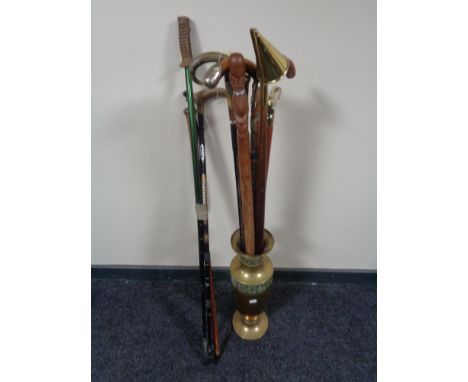 A brass embossed stick stand containing a large quantity of assorted walking sticks, some with silver mounts, candle snuffer 