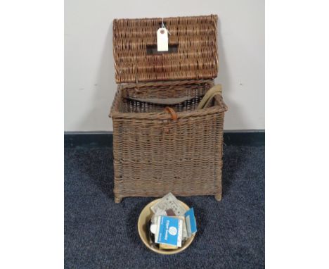 An early 20th century wicker fisherman's stool basket with canvas and leather straps, containing vintage fishing tackle.  