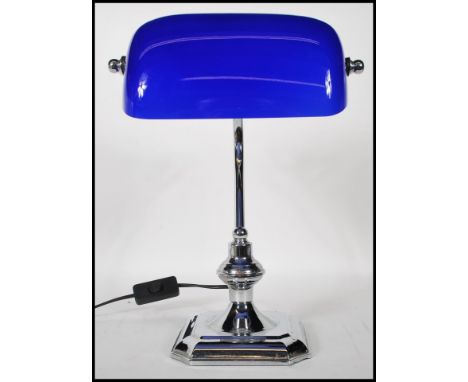 A vintage style bankers desk lamp having an adjustable blue glass shade raised on a chromed support and stepped brass base.