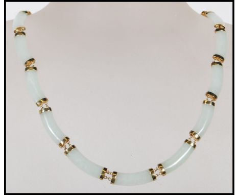 A Chinese jade spacer necklace constructed from 16 curved jade panels mounted on 14ct gold mounts with a round tongue in groo