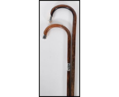 Two 20th Century walking stick canes with bamboo shafts and crook handles both terminating in silver knops, one being hallmar