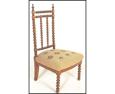 A 19th Century Victorian bobbin framed nursing chair having a stick back with stuffed needlework seat stitched in a fleur de 