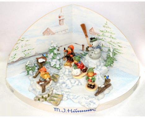 A GOEBEL WINTER TABLEAU INCORPORATING M.J. HUMMEL FIGURES ON SCENIC PICTORIAL CARD WINTER STAND, 45CM L
