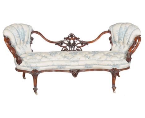  A Victorian carved walnut and button upholstered settee,   circa 1860, the shaped back with twin rests centred by an elabora