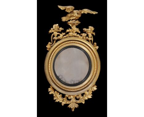  A George III carved giltwood convex wall mirror,   circa 1800, the circular plate within a reed moulded ebonised sight edge 