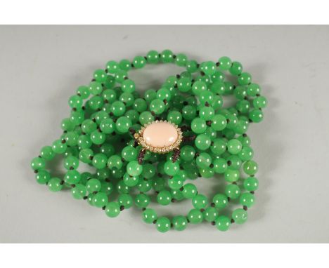 A VERY GOOD TRIPLE ROW JADE NECKLACE with oval coral and diamond clasp.