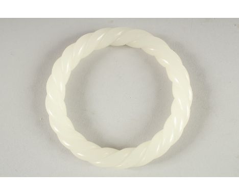 A WHITE JADE TWIST BANGLE 3.25ins diameter.