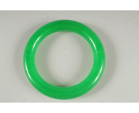 AN APPLE GREEN JADE BANGLE.  3.25ins diameter.