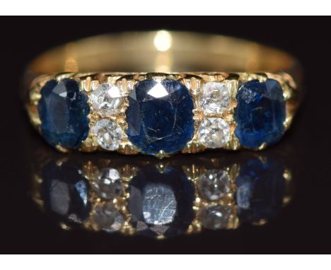 An 18ct gold ring set with three sapphires and four diamonds, size Q