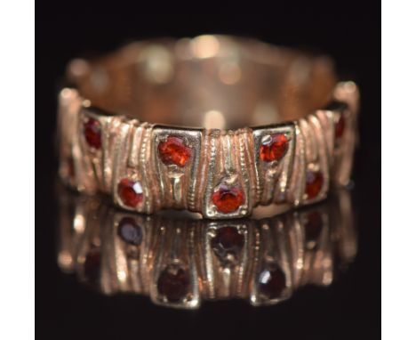 A 9ct gold eternity ring with textured finish set with garnets, 3.6g, size K