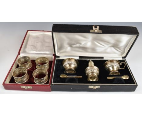 Cased set of four silver napkin rings with embossed decoration and marked sterling silver, together with a cased cruet set al
